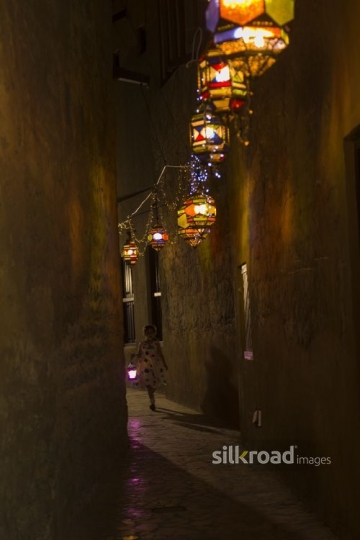 Middle Eastern girl running through the pathway decorated by Ramadan Lanterns|-