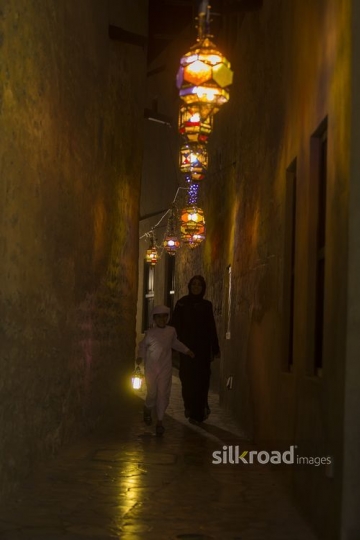 Arab son running infront of his mother carrying a Ramadan Lantern|-