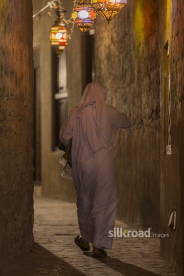 Middle Eastern man walking through they alleyway decorated by Ramadan Lanterns|-