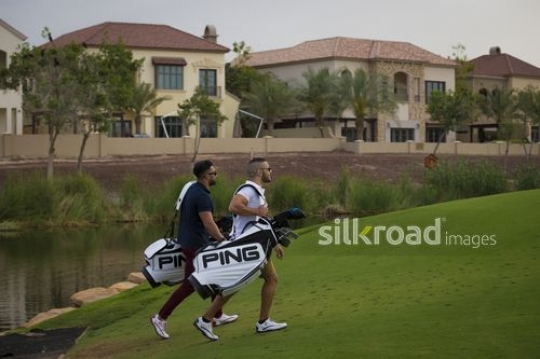 Arab men carrying Golf bags walking at the Golf Resort|-