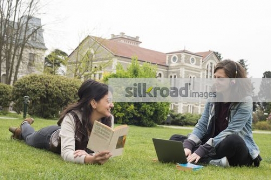 Women sitting on the grass together talking |