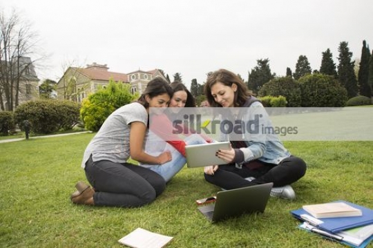Friends sitting together on the grass talking|
