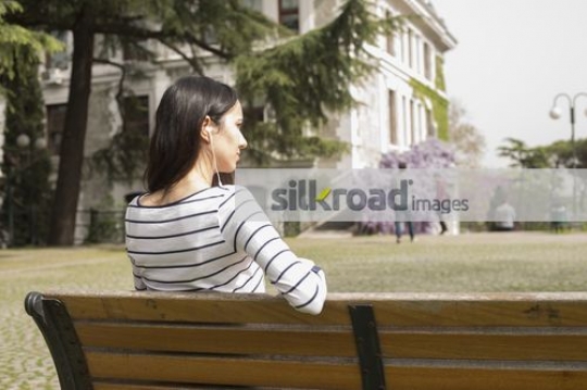 Student on the bench listening to music|