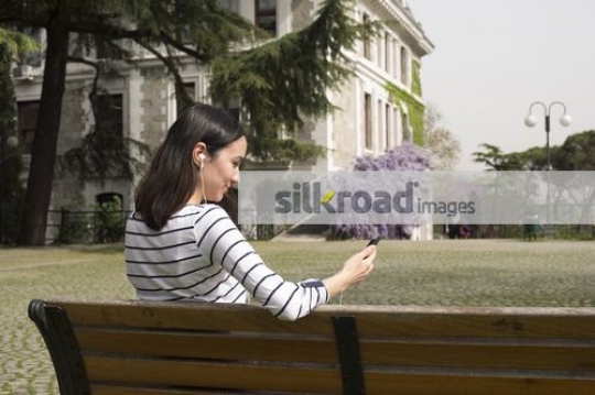Woman sitting on the bench using the mobile|