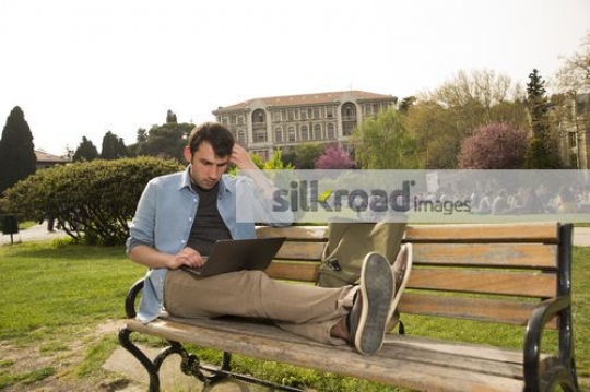 Man sitting on the bench using the device|