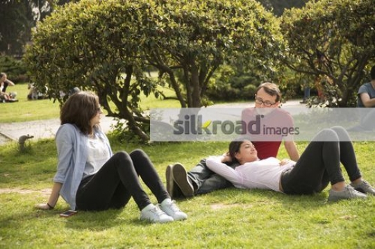 Friends sitting on the grass talking to each other|