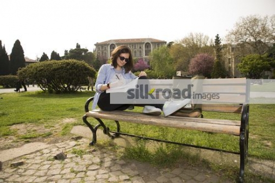 Student sitting on the bench reading a book |
