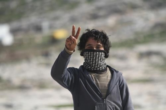 Young Palestinian demonstrators masked and making the V-sign at Bab al-Shams or Gate of the Sun