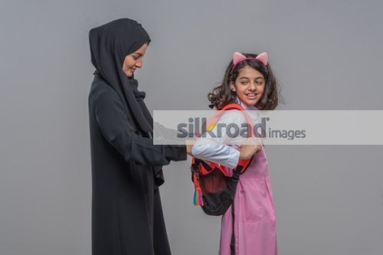 Middle Eastern woman preparing the young girl for school|