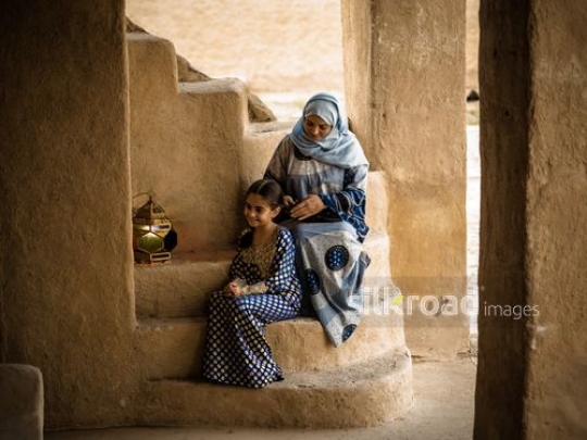Mother making braids for daughter|-