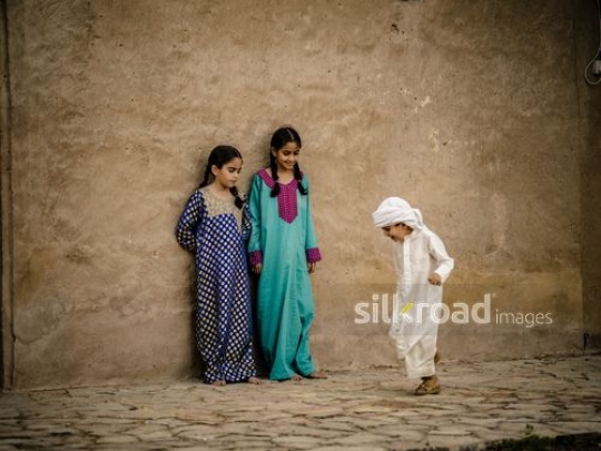 Boy jumping and playing with sisters outside|-