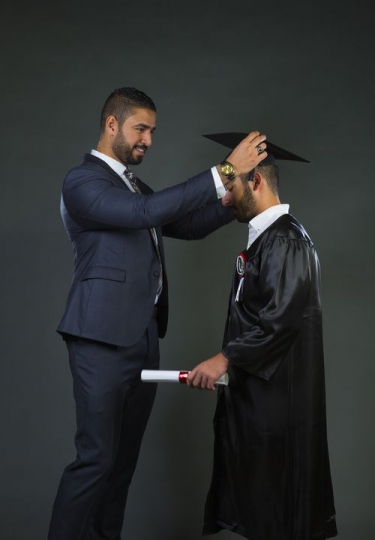 Proud father helping his son with graduation cap