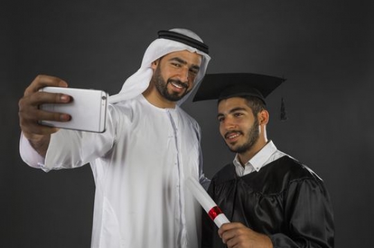 Middle Eastern father taking a selfie with his son graduating
