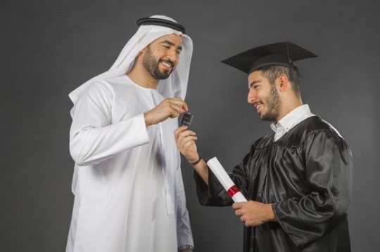 Medium shot of an Arab man gifting his son on graduation