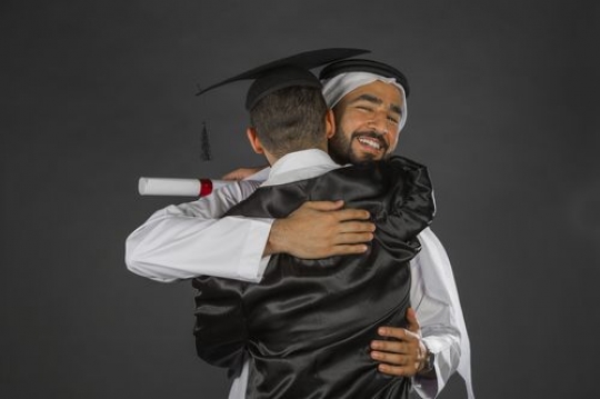 Middle Eastern father hugging his son on graduation