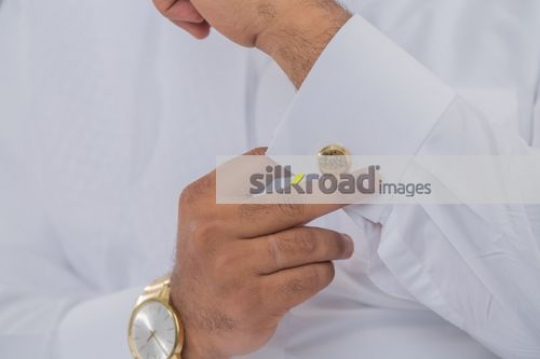 Middle Eastern man fixing the cufflink|